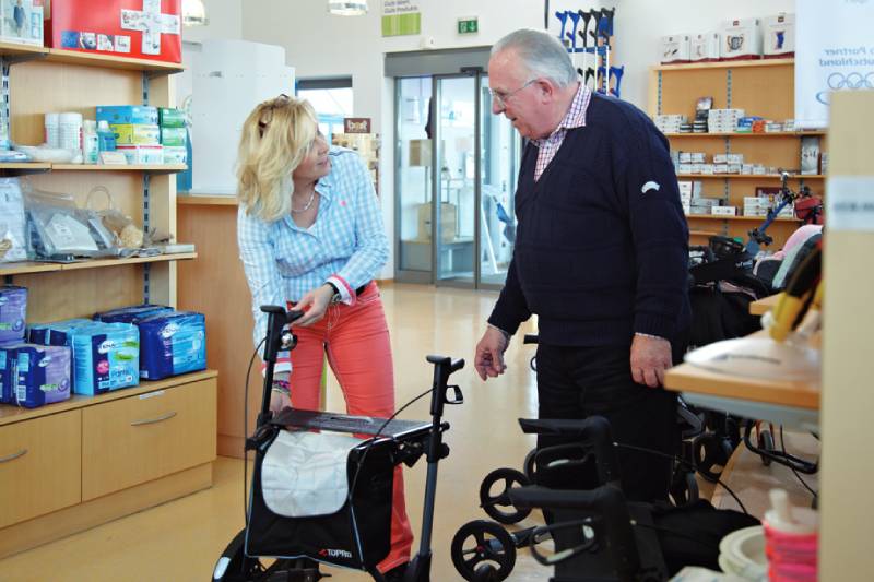 Verkäferin erklärt Mann einen Rollator