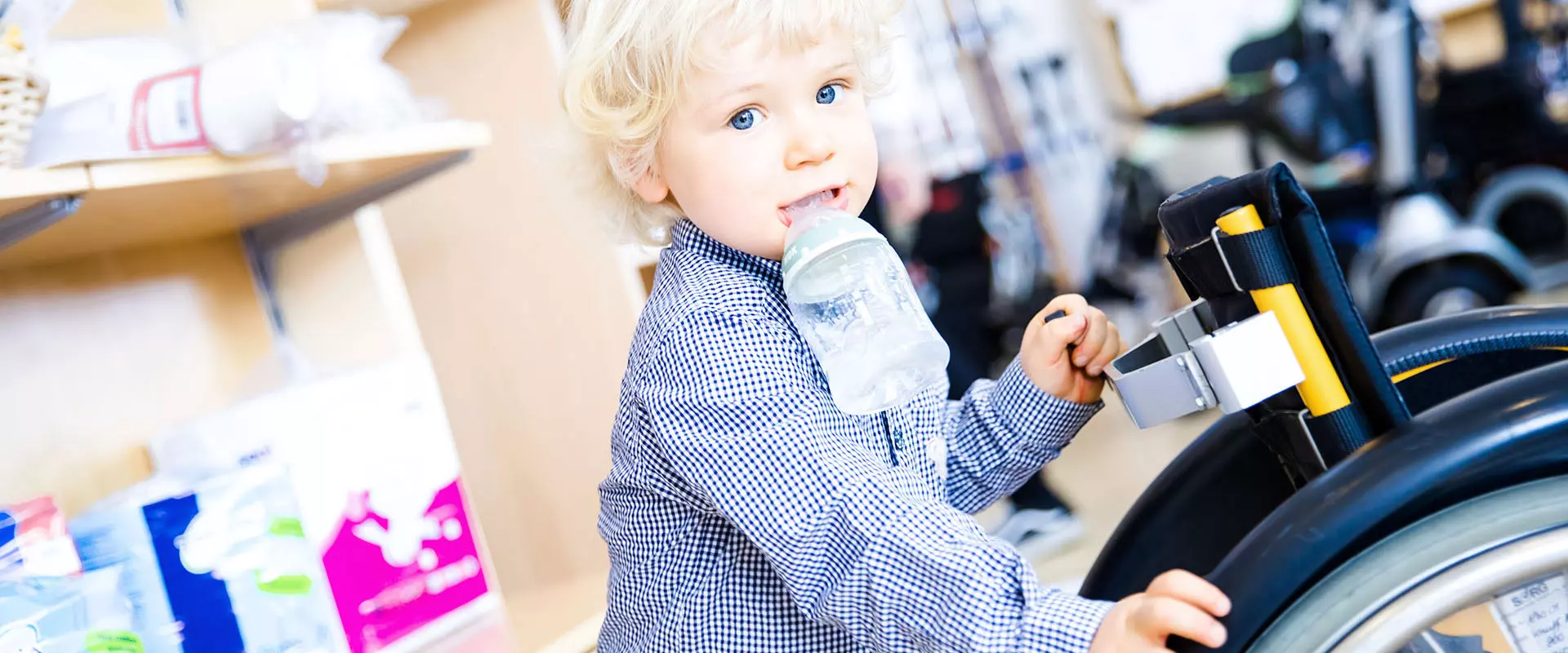 Sanitätskaufhaus Kellner - Relaunch 2025 - Kinderrehabilitation - zufriedenes Kind mit Trinkflasche in der Rollstuhl und Rollator Abteilung